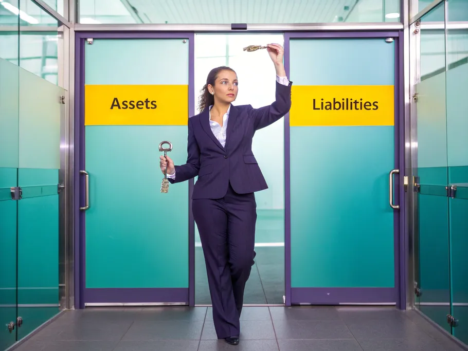 Businesswoman balancing keys and a feather symbolizing assets and liabilities in accounting
