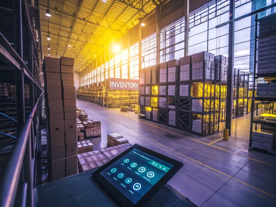 Overhead view of a modern warehouse with organized shelves and a digital tablet displaying inventory data.