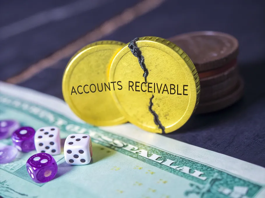 Extreme close-up of a gold coin labeled 'Accounts Receivable' with a crack, symbolizing financial fragility.
