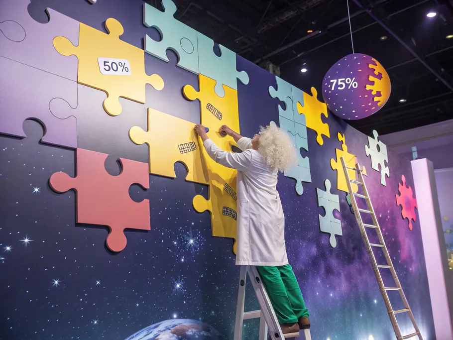 A whimsical illustration of a scientist adding puzzle pieces in space, representing the process costing method.