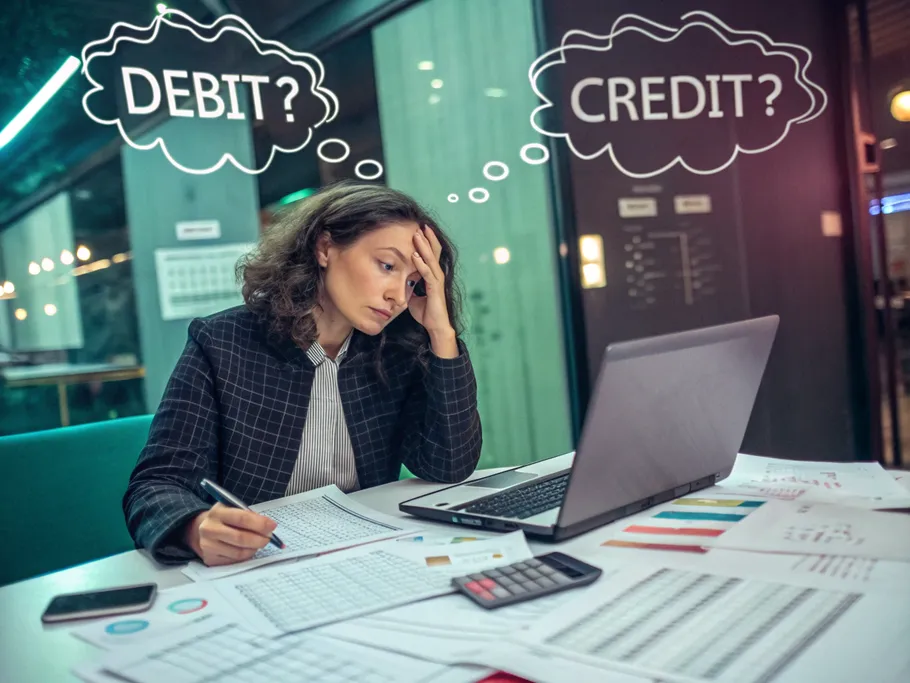 Young female tech startup founder overwhelmed by financial reports, pondering debit and credit.