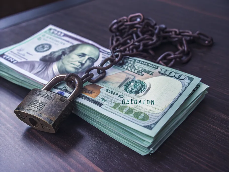 Close-up of a stack of US hundred-dollar bills secured by a padlock and chain, symbolizing unearned revenue.